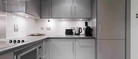 A modern kitchen with stainless steel appliances, white cabinetry, and a built-in oven.
