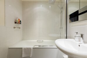 Ein modernes Badezimmer mit einer Badewanne, einem Waschbecken und einer Dusche mit Glastür.