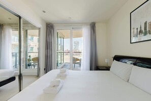 Ein Hotelzimmer mit Bett, Stuhl, Schreibtisch und Blick auf Gebäude durch das Fenster.