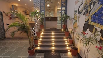 Una escalera con plantas en macetas, una recepción y un mural de un elefante.