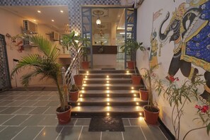 A staircase with potted plants, a reception desk, and a mural of an elephant. - Aora Hotels And Villas  (Udaipur)