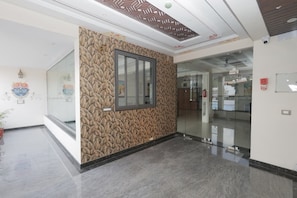 A modern interior with a patterned wall, a glass door, and a ceiling with geometric design. - Aora Hotels And Villas (Udaipur)