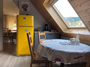 A kitchen with a yellow refrigerator, wooden cabinets, a dining table with a white tablecloth, and a view through a skylight.