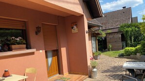 Eine Terrasse mit Tisch und Stühlen, einer Tür und einem kleinen Garten.