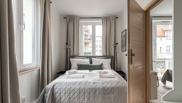 Una camera da letto con un letto, tende, una porta e una finestra.