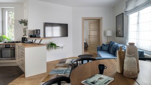 Una cucina moderna con isola integrata, una TV a schermo piatto e un'area pranzo con tavolo e sedie.