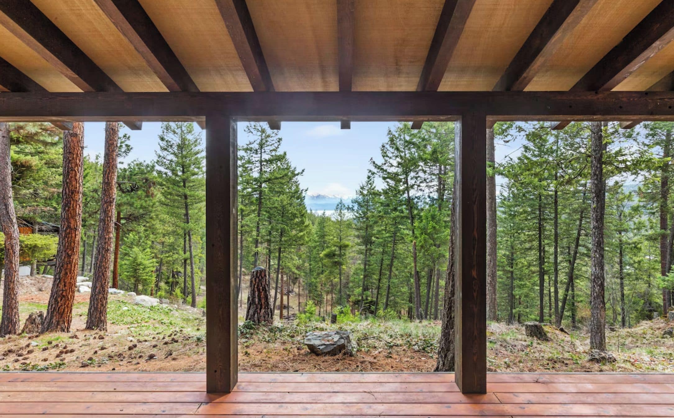 Una terraza de madera con vistas a un bosque y montañas.