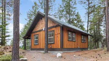 Eine Hütte mit Satteldach, Holzverkleidung und mehreren Fenstern.