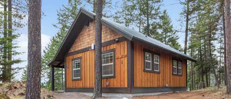 A cabin with a gabled roof, wooden siding, and multiple windows.