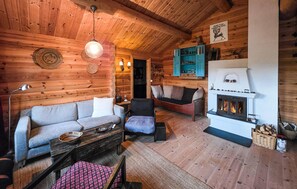 A cozy log cabin interior with a sofa, armchair, and a fireplace. - Amazing home in Rauland with sauna (Rauland)
