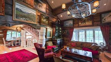A log cabin interior with a dining area, a fireplace, and a large window.