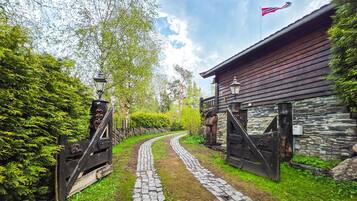 A rustic building with a stone facade, a cobblestone path leading to it, and a flag on top.