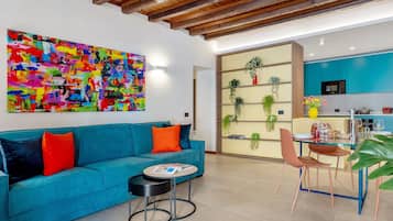 Ein modernes Wohnzimmer mit einem blauen Sofa, einem Couchtisch und einem farbenfrohen, abstrakten Gemälde an der Wand.