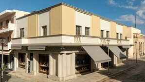 Ein zweistöckiges Gebäude mit flacher Fassade, großen Fenstern und einer überdachten Außenbereich-Sitzgelegenheit.