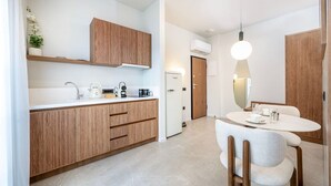Eine moderne Küche mit Holzschränken, einer weißen Arbeitsplatte und einem Essbereich mit rundem Tisch und Stühlen.