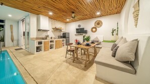 Una cocina moderna con comedor, piscina y sala de estar con sofá.