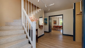 A staircase with a white railing, a dining area with wooden flooring, and a hallway leading to another room. - 🏡 Renovated family villa with swimming pool, private garden, lake view & view of Menthon Castle and the surrounding mountains 🏔️ (Menthon-Saint-Bernard)