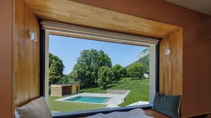 A room with a large sliding glass door leading to a pool area, a wooden ceiling, and a view of a green landscape. - 🏡 Renovated family villa with swimming pool, private garden, lake view & view of Menthon Castle and the surrounding mountains 🏔️ (Menthon-Saint-Bernard)