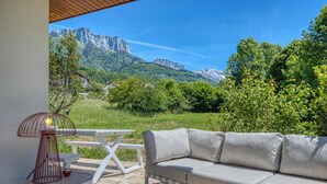 An outdoor seating area with a sofa, table, and lamp, overlooking a mountainous landscape. - 🏡 Renovated family villa with swimming pool, private garden, lake view & view of Menthon Castle and the surrounding mountains 🏔️ (Menthon-Saint-Bernard)