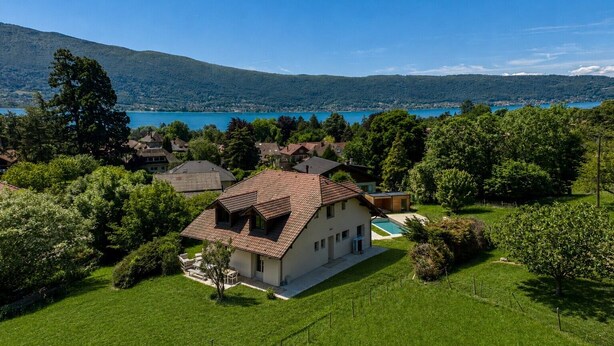 A house with a sloped roof, surrounded by lush greenery and a lake view. - 🏡 Renovated family villa with swimming pool, private garden, lake view & view of Menthon Castle and the surrounding mountains 🏔️ (Menthon-Saint-Bernard)