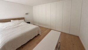 Ett sovrum med en säng, ett sängbord, en garderob och en bänk.