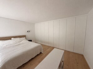 Ein Schlafzimmer mit Bett, Nachttisch, Kleiderschrank und einer Bank.