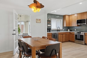 A modern kitchen with wooden cabinets, a built-in oven, and a dining area with a wooden table and chairs. - NEW! Designer Home - King Beds, Glass Sunroom, Game Room, BBQ (Southfield)