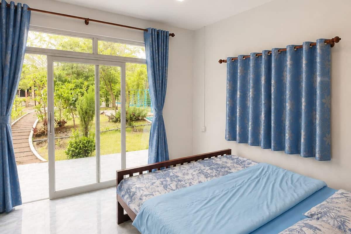 Un dormitorio con cama, cortinas y vistas a un jardín.