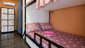 Una cama individual con ropa de cama rosa, un armario con adhesivos de mariposas y un equipo de aire acondicionado.