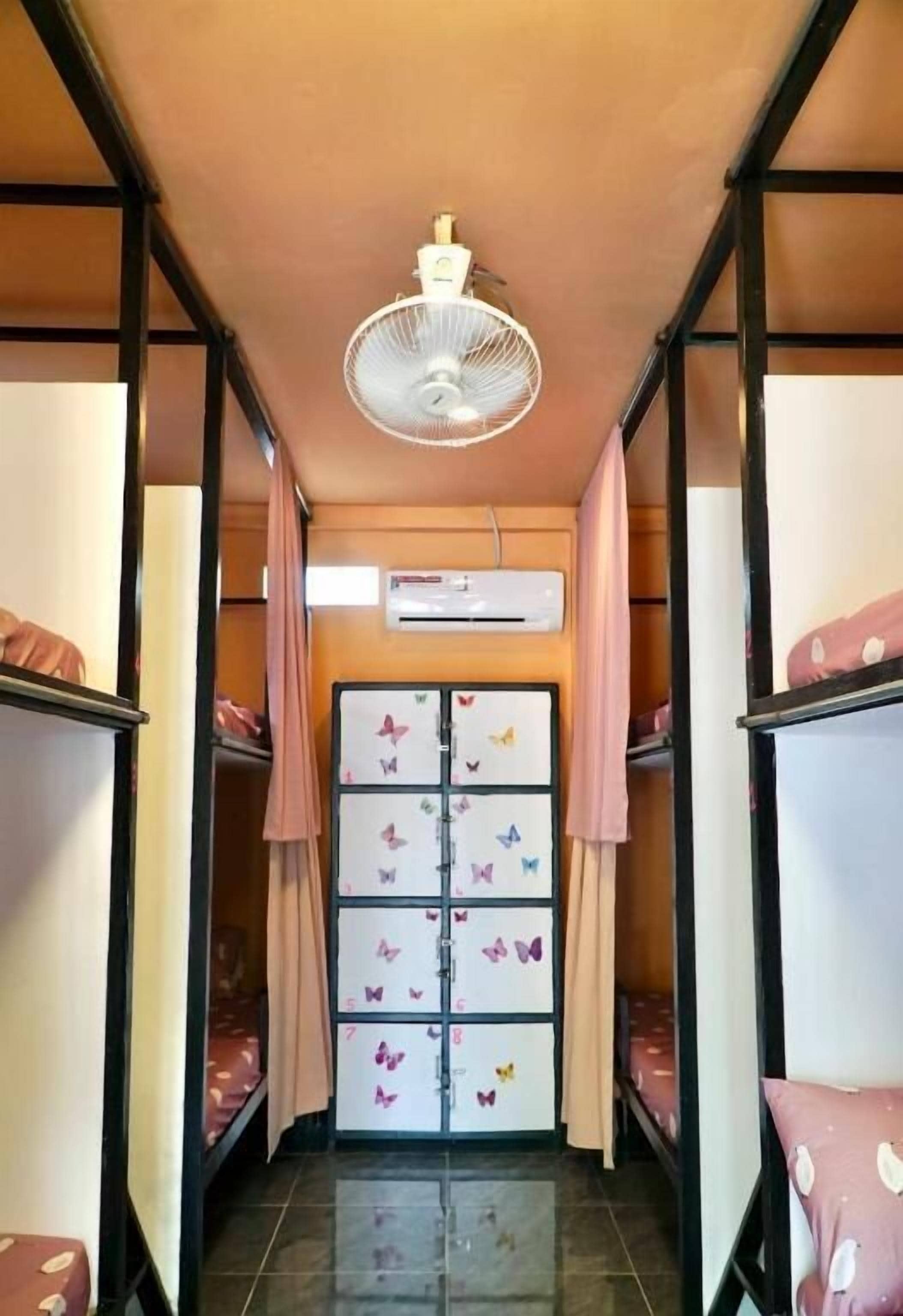 Een slaapkamer met stapelbedden, een plafondventilator, een airconditioning en opbergkasten met vlinderthema.