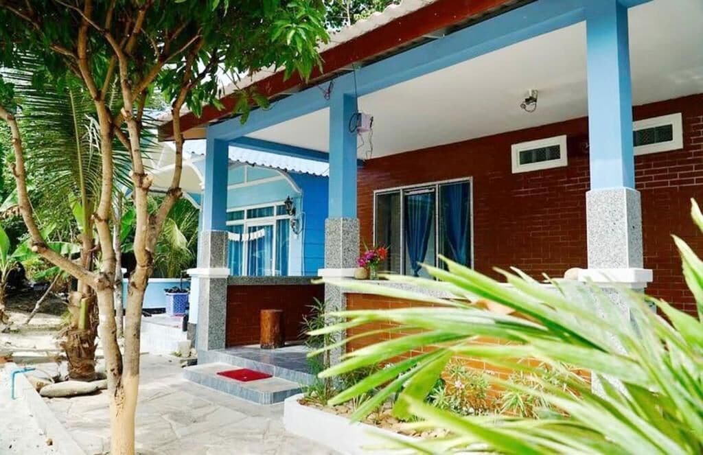 A covered outdoor area with a brick wall, a blue and white structure, and a palm tree.