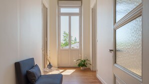 A hallway with a sofa, a potted plant, and a door leading to a balcony. - Entire Villa: Eyrans, France – 10 Guests, 5 Bedrooms, 5 Beds, 4 Bathrooms (Eyrans)