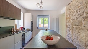 A modern kitchen with a central island, a window with a view, and a stone accent wall. - Entire Villa: Eyrans, France – 10 Guests, 5 Bedrooms, 5 Beds, 4 Bathrooms (Eyrans)