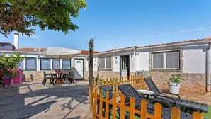 Une propriété résidentielle dotée d’une terrasse, d’un espace salon extérieur, d’une clôture en bois et d’un mur en pierre.