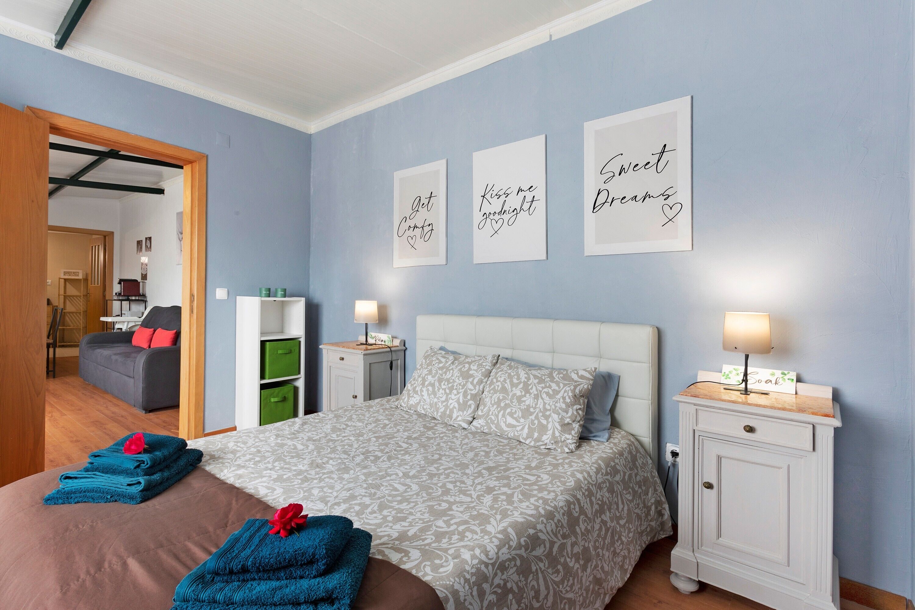 Una camera da letto con un letto, comodini, un guardaroba e tre opere d'arte appese alle pareti.