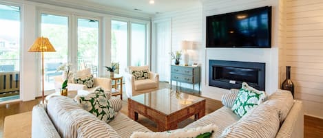 A living room with a sofa, armchairs, a coffee table, a TV, and a fireplace.