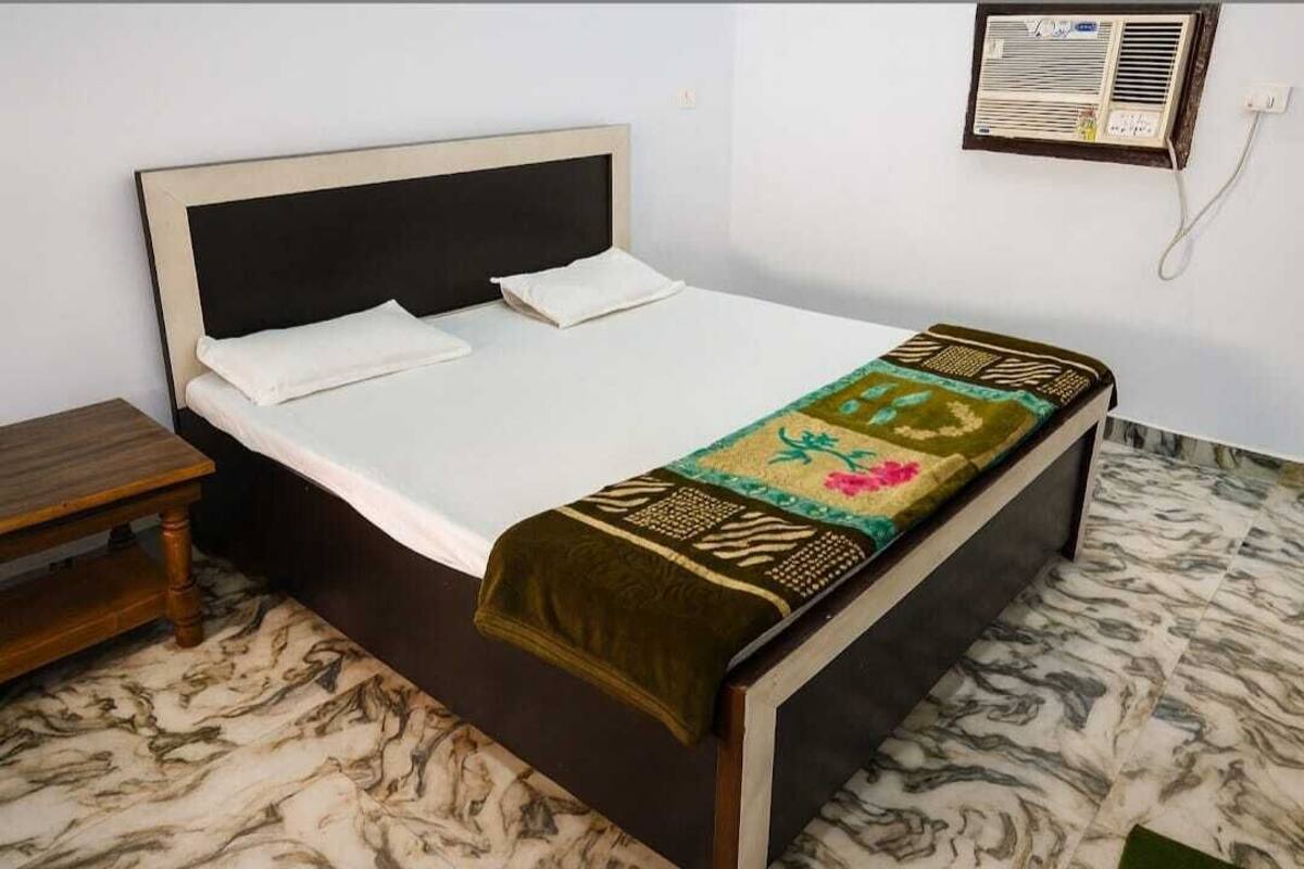 A single bed with a headboard, a bedside table, and a wall-mounted air conditioner.