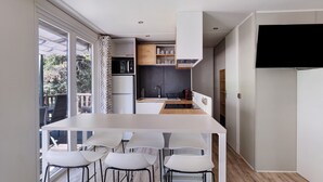 Eine moderne Küche mit einer zentralen Kochinsel, weißen Barhocker und einem großen Fenster.