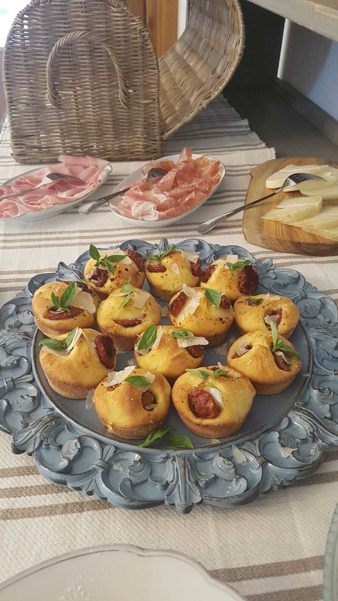A table with a decorative blue plate holding small pastries, a wicker basket, and a plate of sliced meats.