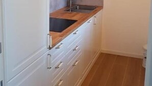 A narrow kitchen with white cabinets, a wooden countertop, and a single sink. - Agriturismo Resort Il Foionco (Massa Marittima)