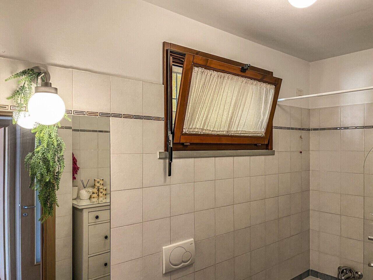 Un baño con ventana, un perchero, un espejo y una lámpara.