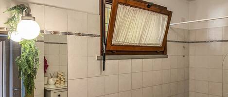 Un baño con ventana, un perchero, un espejo y una lámpara.