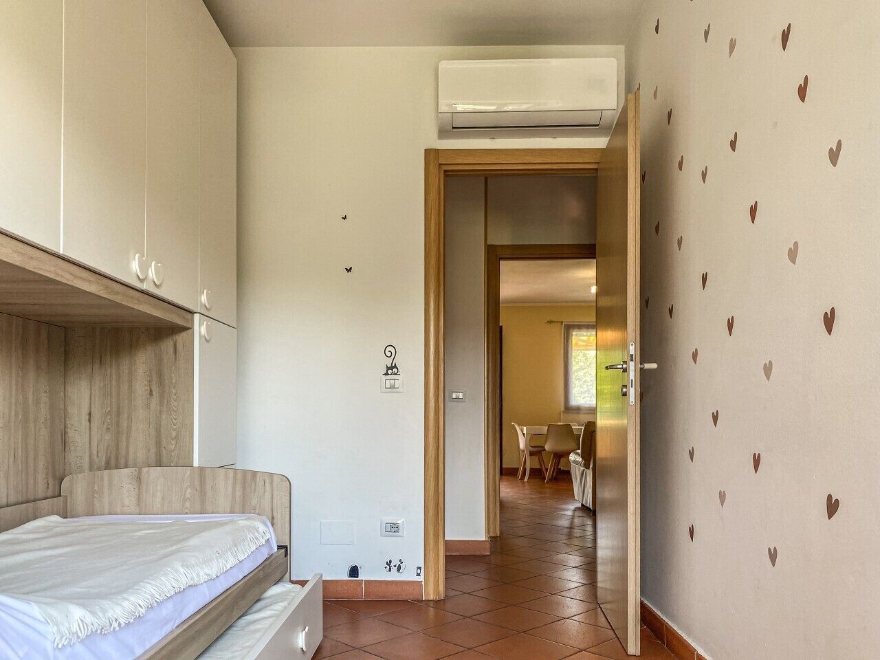 A bedroom with a bed, wardrobe, and an open door leading to a dining area.