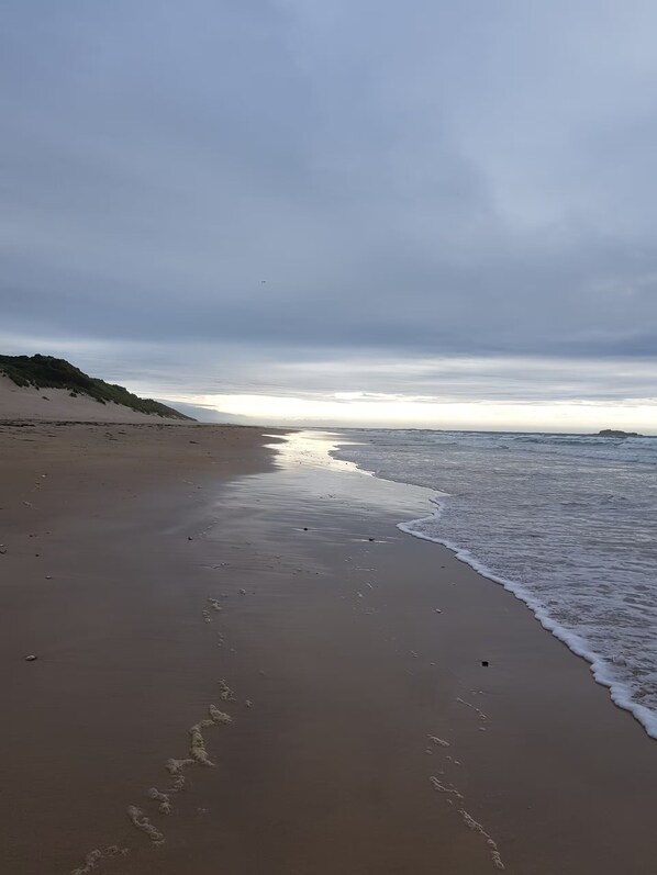 A beach with a sandy shore, gentle waves, and a cloudy sky. - Chic, modern, comfortable 2-bed apt directly opposite beach in town centre (Portrush)