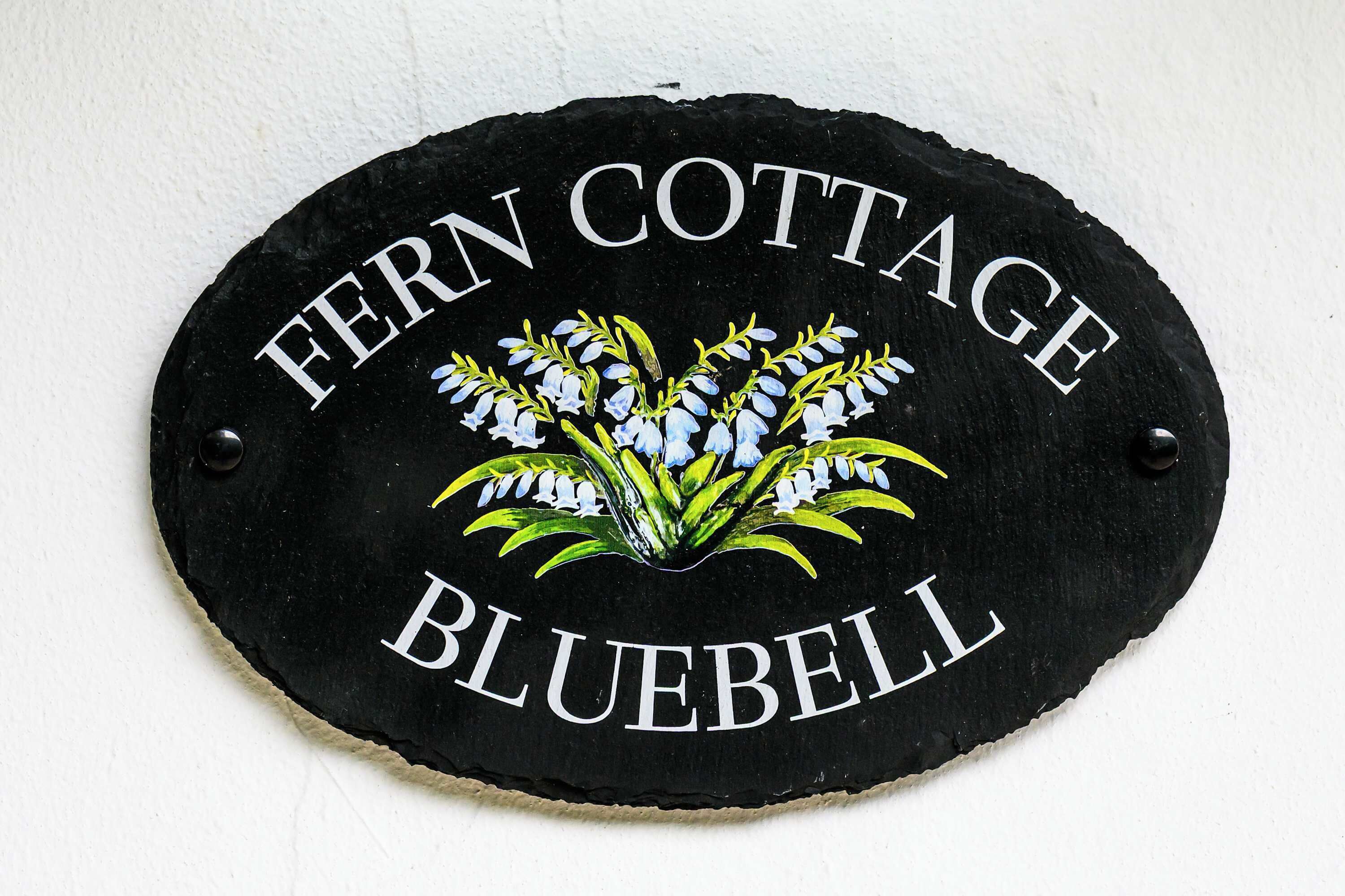Un letrero con el texto 'Fern Cottage Bluebell' y un diseño floral.