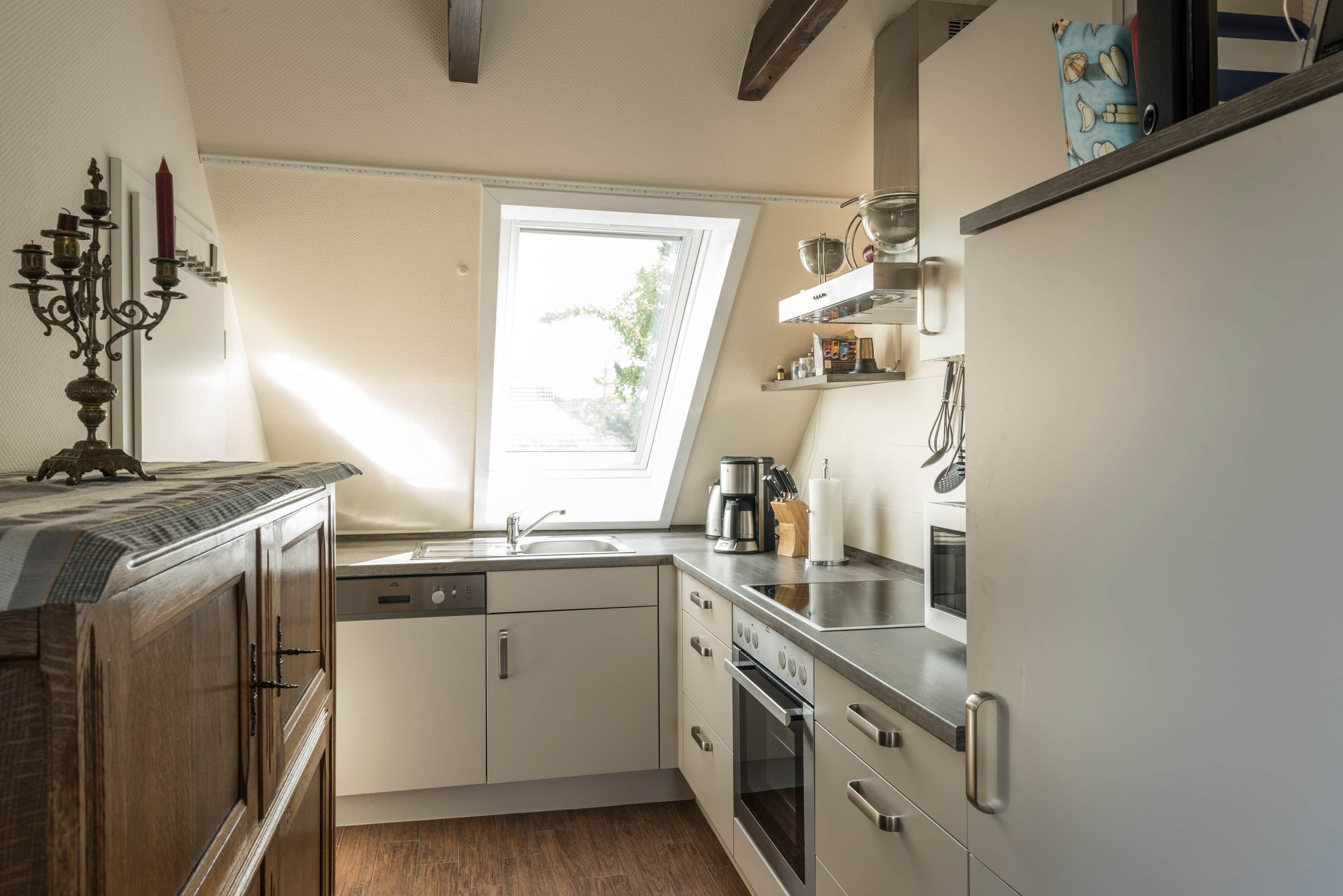 Een keuken met een raam, een koffiezetapparaat en een fornuis.