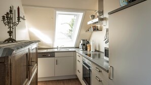A kitchen with a window, a coffee maker, and a stove. - Harleblick Carolinensiel (Wittmund)
