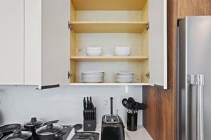 A kitchen with a wooden cabinet, a stainless steel refrigerator, and a toaster.