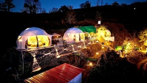 A series of dome-shaped structures with a staircase leading to a higher level, surrounded by trees and a rocky landscape. - Manzil Escapes (Dhanaulti)