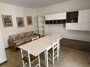 Ein Zimmer mit einem weißen Tisch, weißen Stühlen, einer blumigen Couch und einer Wand mit drei gerahmten Bildern.